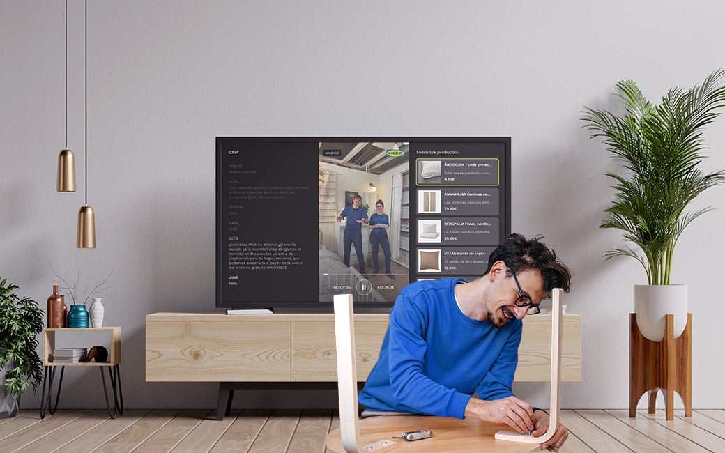 Hombre montando un mueble con una TV que muestra la Living App de IKEA.