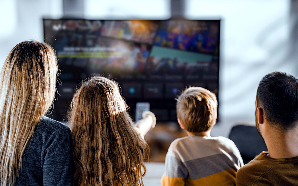 Familia viendo la TV con el menú principal de Movistar Plus+ en pantalla.