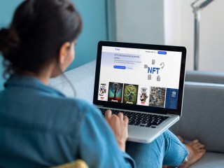 Mujer viendo en un portátil la web de Telefónica Marketplace NFTs
