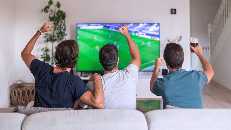 Tres hombres viendo un partido de fútbol.