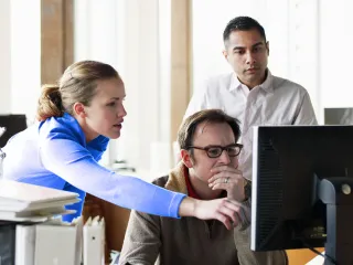 Tres personas mirando la pantalla de un ordenador
