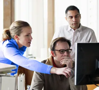 Tres personas mirando la pantalla de un ordenador