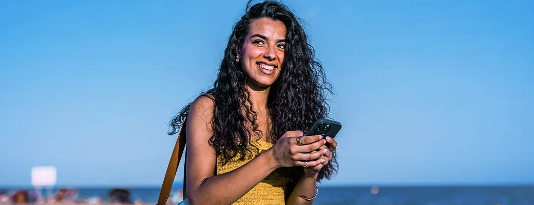 Mujer viendo el móvil en la playa
