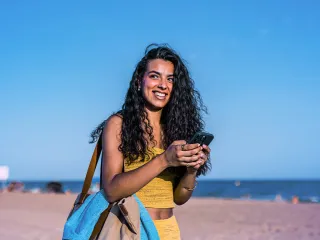 Mujer viendo el móvil en la playa